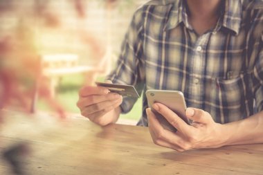 Kredi kartı tutan ve akıllı telefon kullanarak eller. Online alışveriş