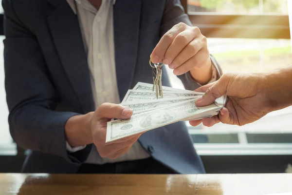 Agents are giving house keys of customer and holding dollar us b — Stock Photo, Image
