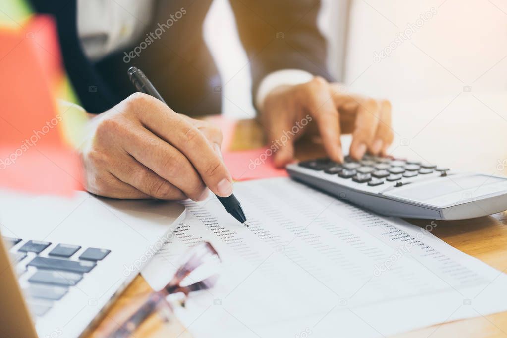 Close up Business man using calculator and laptop computer for c