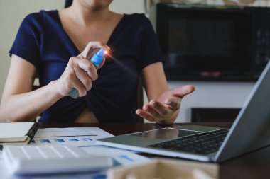 Maskeli kadın Corona virüsünü veya Cvid-19 'u öldürmek için eline alkol püskürtüyor. ev kavramından çalışma.