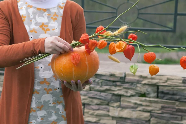 Genç kız bir turuncu kabak holding ve çiçekler.