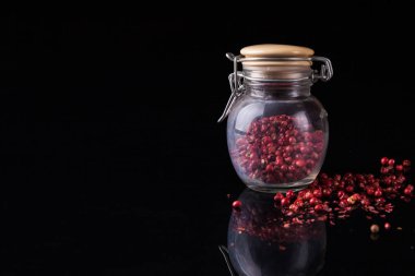 Bezelye biber siyah arka plan üzerine cam kavanozda