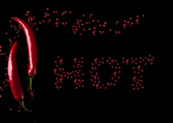 Κόκκινη καυτερή πιπεριά σε μαύρο φόντο. Η λέξη καυτά πιπέρια — Φωτογραφία Αρχείου