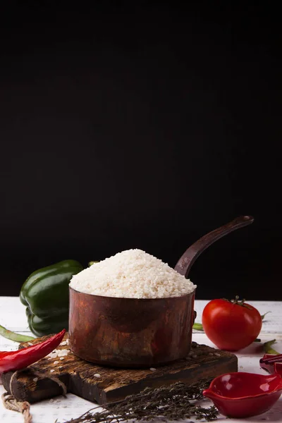 Demir güveç ahşap kesme tahtası üzerinde sebzeli pirinç. Siyah arka plan kopya alanı ile