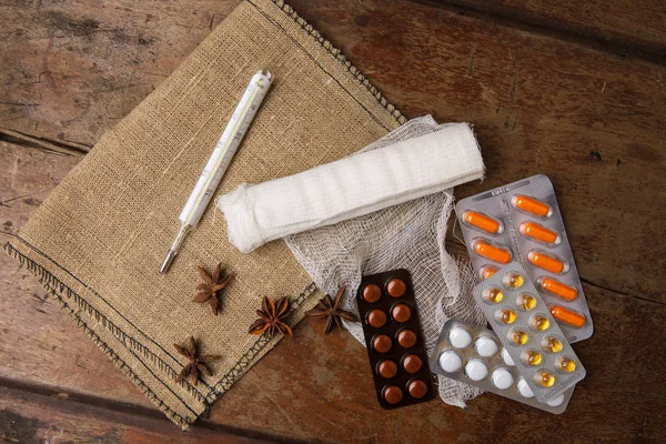 Tıbbi sargı, hap ve termometre ahşap arka plan üzerinde. Üstten Görünüm