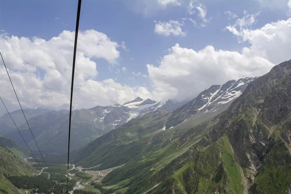 Himmel in den Wolken grün und Schnee auf den Bergen und Seilbahnen, Nordkaukasus-Elbrus-Region. — Stockfoto