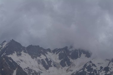Karla kaplı dağ silsilesi bulutların arkasına saklanarak Elbrus, Kabardey-çatışmalar işgalciler, Rusya eğimi görünümünden.