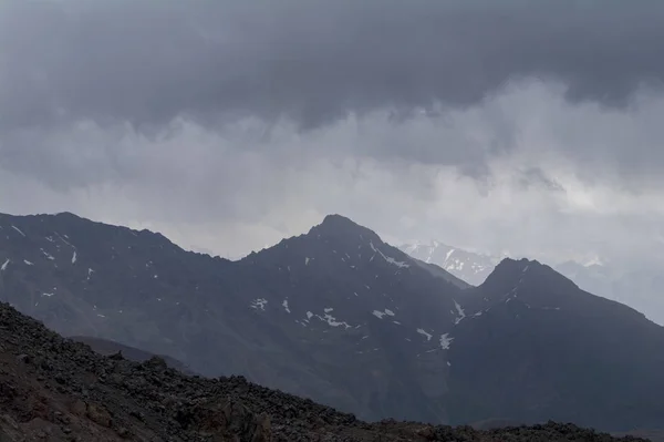 エルブラス山、北コーカサス、ロシアの斜面から見たロッキー トップと、それらの上の雲. — ストック写真