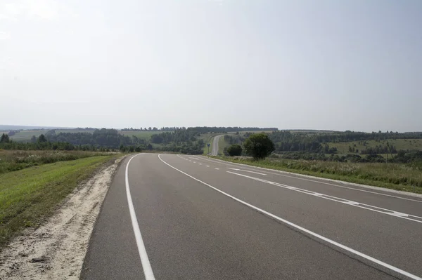 Asfalt yol ile beyaz markings tepelik kırsal gidiş.