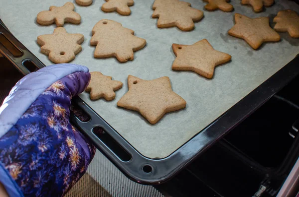 Vlose-up vue partielle de la personne qui met des biscuits de Noël au four — Photo
