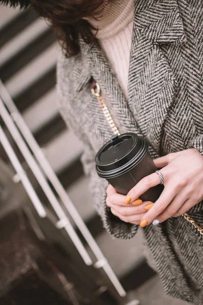 Una taza de café en las manos de las mujeres. Hermosa joven morena con abrigo gris . —  Fotos de Stock