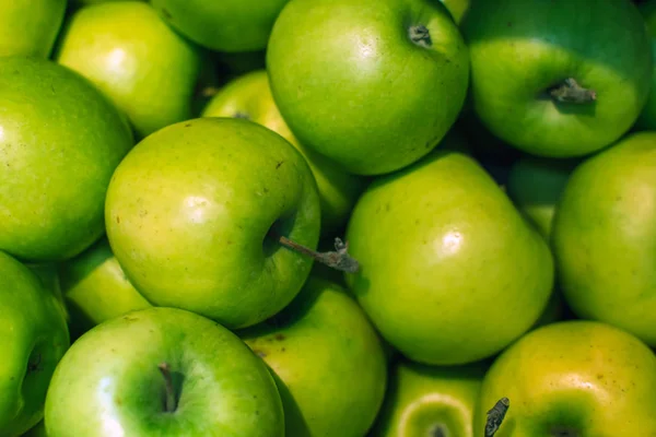 Groene appels achtergrond vol sinaasappels. Verse groene appel op de markt. — Stockfoto