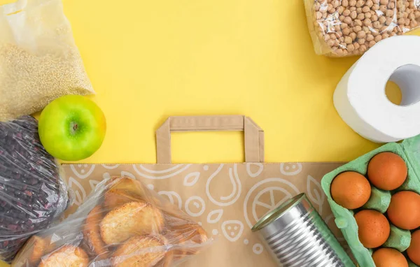 Karantina süresi için yiyecekler, fotokopi alanı olan sarı arka planda yatıyordu. Yumurta, makarna, fasulye, tuvalet kağıdı, elma ve biraz seleal. Kriz gıda malzemeleri. Teslimat, bağış konsepti.