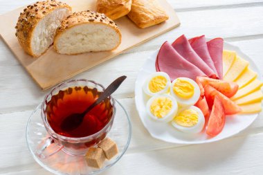 Yumuşak yumurta, peynir, jambon taze ekmek ve fincan kahve ya da hafif ahşap zemin üzerinde çay ile taze ve lezzetli bir kahvaltı. Sağlık içerikli kahvaltı..