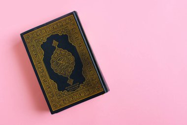 Açık pembe arkaplan üzerine Kur 'an. Boşluk mesajı. Ramazan Kareem. Üst görünüm.