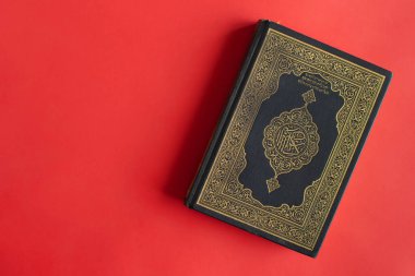 Düz bordo arka planda Kur 'an. Üst görünüm.