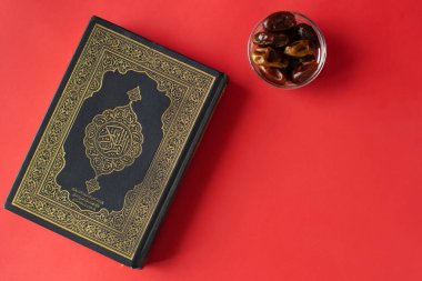 Düz bordo arka planda Kur 'an. Randevular kasede. Ramazan Kareem selamlar. Üst görüntü.