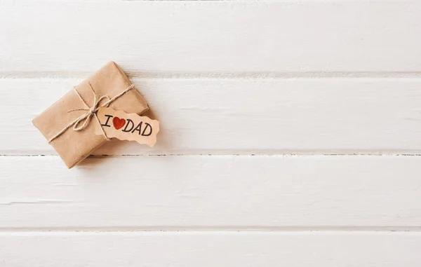 Cadeaudoosje met een tag op witte houten ondergrond. Vaderdag of verjaardagsconcept. — Stockfoto