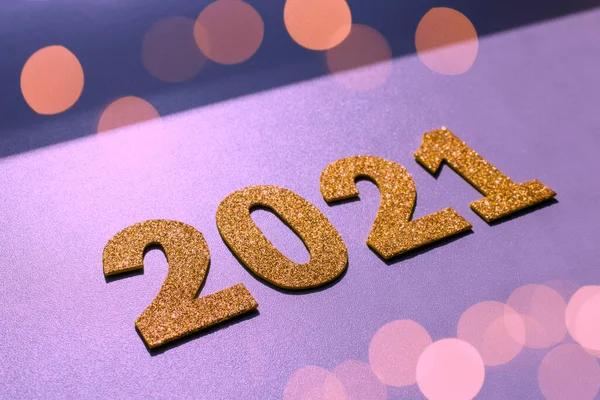 Happy New year 2021 celebration. Gold numeral 2021 and lights on purple background. Flat lay