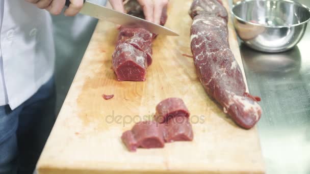 Chef-kok snijdt rauwe bevriezen vlees op snijplank in industriële keuken. — Stockvideo