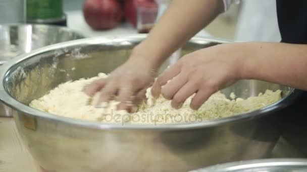 I køkkenet, kokken flosser hænder dej i en stor metal skål . – Stock-video