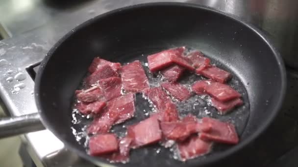 Cook roasts meat pieces in frying pan on electric stove — Stock Video