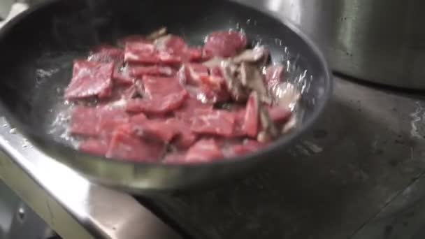 Cook roasts meat in frying pan on professional kitchen in restaurant — Stock Video