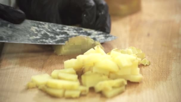 Chef-kok in zwarte handschoenen met een mes snijdt de schade van gekookte aardappelen. — Stockvideo