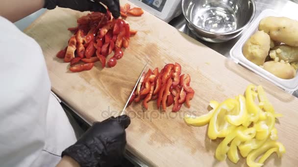 Chef cuts strips red bell peppers on table in industrial kitchen. — Stock Video