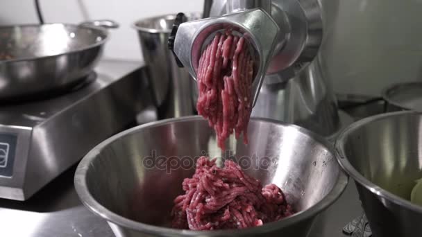 Electric meat grinder of metal scrolls red meat in the kitchen cafe. — Stock Video