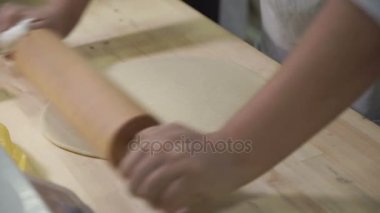 Ahşap bir iskelede şef pişirme için bir oklava kullanarak hamur rulo..