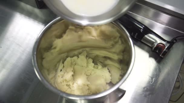Na panela de metal com batatas trituradas o cozinheiro acrescenta o leite fervente — Vídeo de Stock