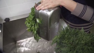 Kadın dolu bir yeşil konteyner ile lavabo üzerinde su dökülen.