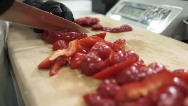 Шеф-кухар розрізає червоний перець на обробній дошці на промисловій кухні — стокове відео