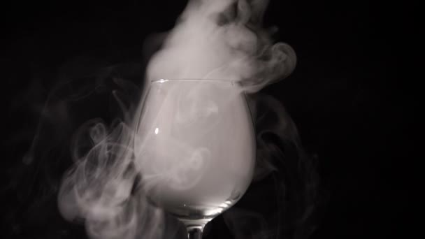 En la oscuridad el humo blanco flotando en un vaso vacío y transparente . — Vídeo de stock