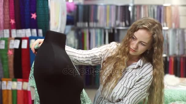 Naaister lay-out stof op etalagepop op zoek naar ideeën voor jurk. — Stockvideo