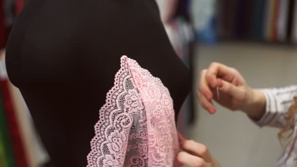 Vendedor de tejidos prepara maniquí suave negro con satén de encaje rosa — Vídeo de stock