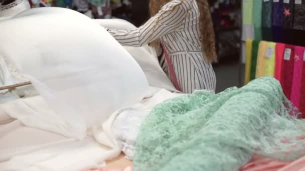 Stof winkel werknemer unwraps roll wit atlas weefsel binnenshuis — Stockvideo