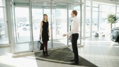 Kadın istemci araçları görüntülemek için çalışan adam otomotiv merkezi olduğunu