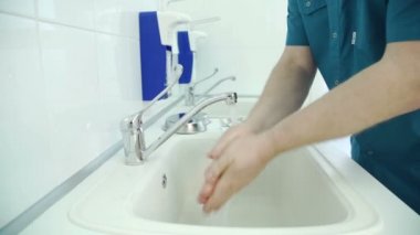 Doktor, dikkatli bir şekilde kontrol önce lavaboda ellerini yıkar.