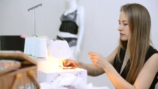 Seamstress sits and white thread inserts into the overlock. — Stock Video