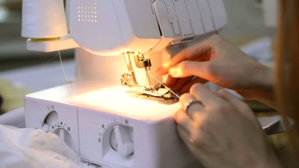 La cucitrice inserisce rapidamente un filo con pinzette overlock bianche . — Video Stock