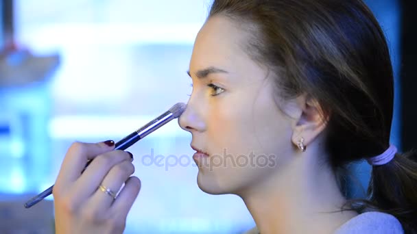 Makeup artist paints powder on brown long-haired model in studio — Stock Video