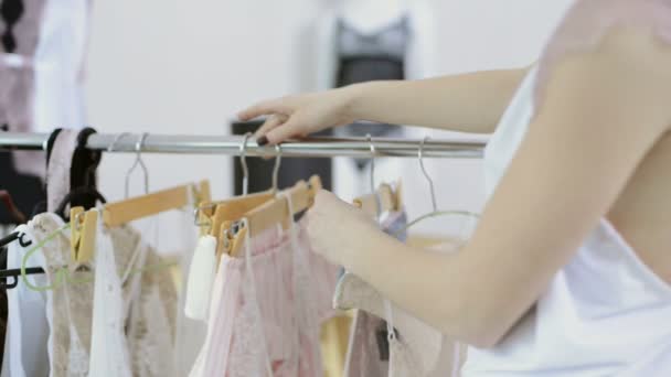Mujer en camisón blanco viene a rack con perchas para elegir ropa interior — Vídeos de Stock
