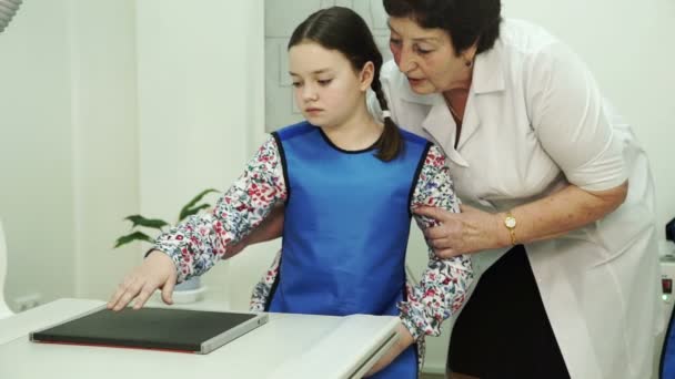 Una enfermera mayor está preparando a una niña para los cepillos de rayos X . — Vídeo de stock