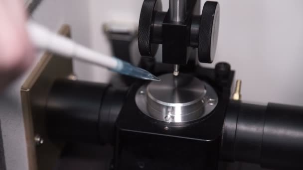 In der Laborhand tropft ein Tropfen Flüssigkeit auf den Chromatographen. — Stockvideo