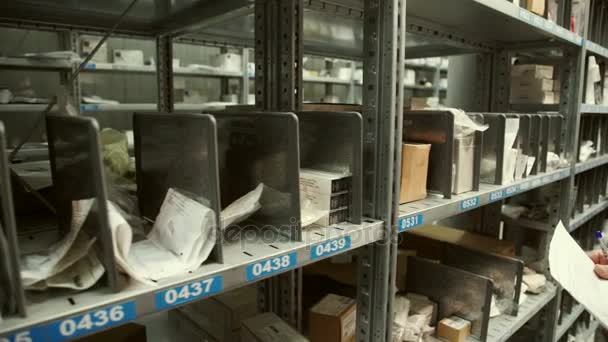 Lagerarbeiter notiert in den Unterlagen und holt eine Schachtel hervor. — Stockvideo