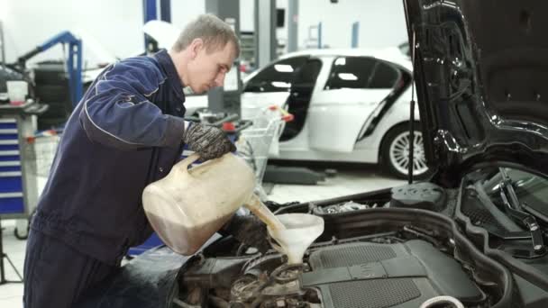 Master Service Center häller olja från en vattenkanna till bilen. — Stockvideo