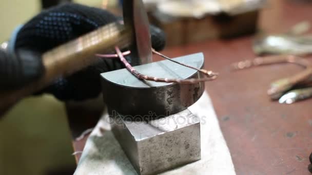 Jeweler beats product with hammer on stand in workshop indoors — Stock Video