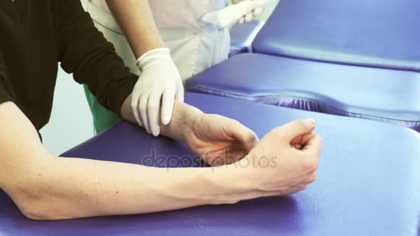 外傷後の患者の腕に包帯をしようとする手袋と看護師します。. — ストック動画